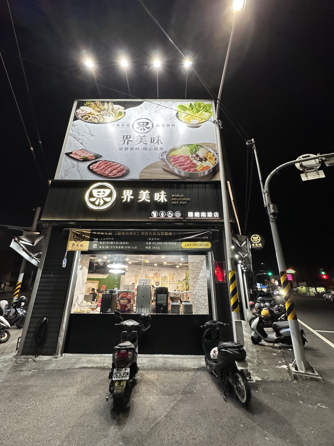 界美味關廟南雄店夜間街道視角，顯示大型帆布、店名與分店字樣